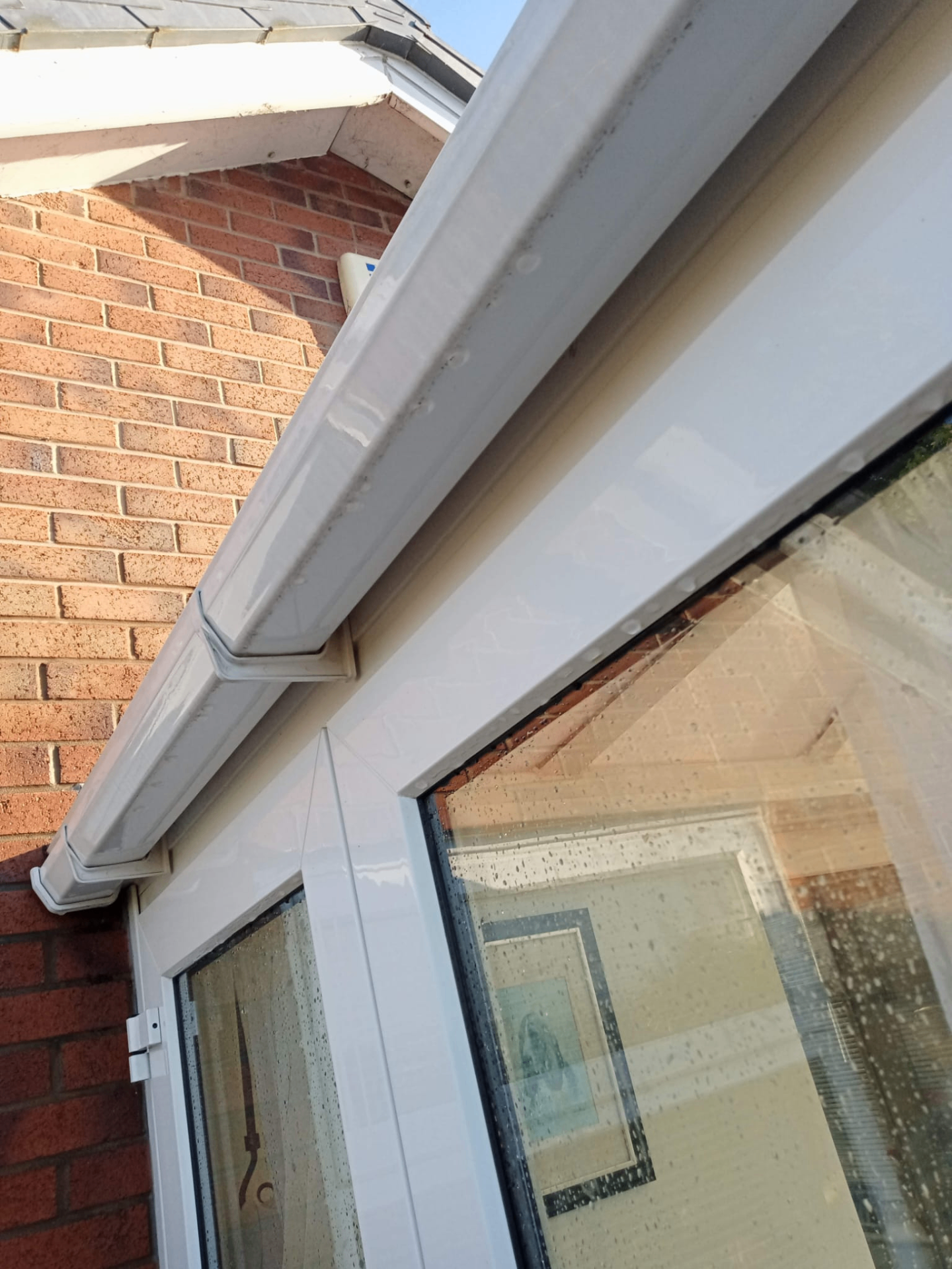 Close-up of white uPVC guttering and fascia boards on red brick home Preston
