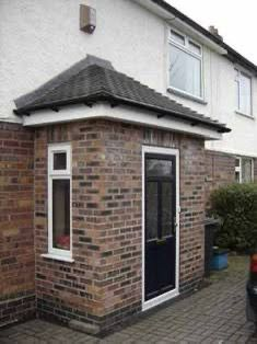 Red brick porch extension with tiled hipped roof and black front door Preston